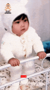 a baby wearing a white hat and overalls is standing on a railing .