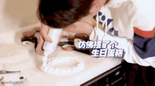 a person is decorating a cake with a bottle of frosting and the word yuedlwatch is on the bottom right