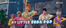 a group of people are dancing in front of a sign that says " my little soda pop "