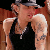 a man wearing a black tank top and a black hat with pmc on it