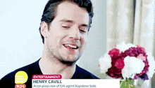 henry cavill is smiling while holding a bouquet of flowers in front of him .