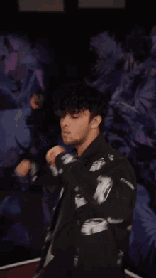 a man wearing a black jacket with cars on it is dancing