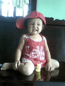 a little girl wearing a red hat and a red tank top that says the lion