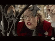 a woman wearing glasses and a red jacket with a cbc logo on her shirt