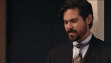 a man with a beard wearing a black suit and tie