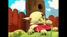 a stuffed animal is sitting on top of a grass covered field next to a wooden fence .