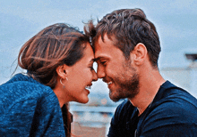 a man and a woman touch their foreheads and smile