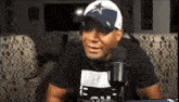 a man wearing a cowboys hat is sitting in front of a microphone in a living room .