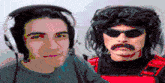 a man wearing headphones and sunglasses stands next to a man with a mustache