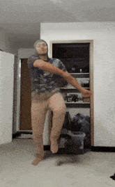a man in a camo shirt is dancing in front of a door