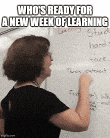 a woman is writing on a whiteboard in front of a whiteboard .