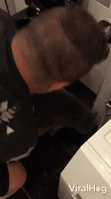 a man sitting in a bathroom next to a washer and dryer with the words viralhog on the bottom