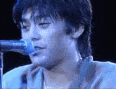 a man is singing into a microphone on stage .