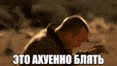 a man with a beard is standing in the desert with a foreign language written on the ground .