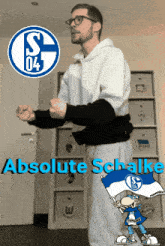 a man stands in front of a wall with absolute schalke written on it