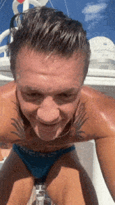 a man with a tattoo on his chest is wearing a pair of blue swim trunks