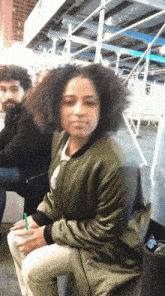 a woman in a green jacket sits in front of a man in a black jacket