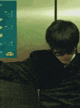 a man wearing glasses stands in front of a hello kitty poster