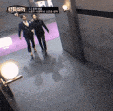 two men in suits are walking down a hallway with a sign that says ' 4 '