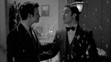 two men in suits and bow ties standing next to each other in the snow
