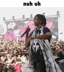 a man singing into a microphone in front of a crowd with the words nuh uh above him