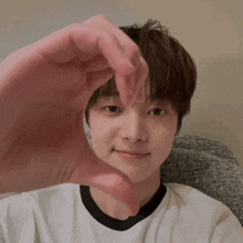 a young boy is making a heart shape with his hands