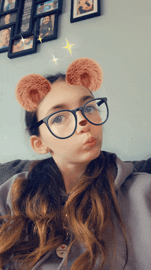 a girl wearing glasses and bear ears makes a face