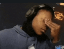 a man wearing headphones covering his face with his hands