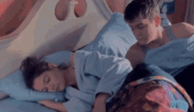 a man and a woman are sleeping in a bed with blue sheets