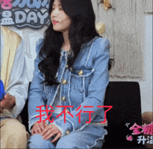 a woman in a denim jacket sits on a couch in front of a sign that says sunday
