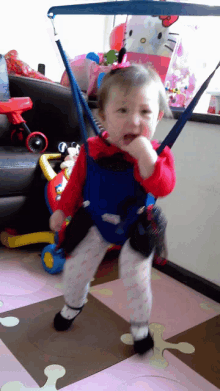 a little girl is standing in a room with a hello kitty bag behind her