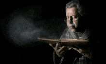 a man with glasses is holding a book in his hands