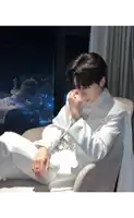 a man in a white suit sits in a chair with his hand on his face
