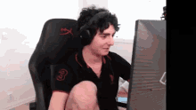 a young man wearing headphones is sitting in a chair in front of a computer monitor .