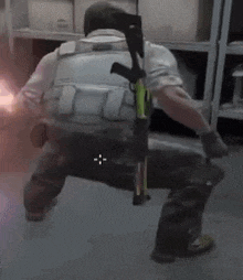 a soldier is kneeling down with a gun on his back in a room .