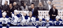 a group of hockey players are sitting on the ice and one of them says believe .
