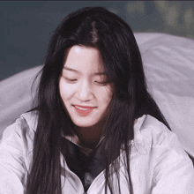 a girl with long black hair is smiling and wearing a white jacket with glory written on it