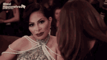 a woman in a pearl dress is talking to another woman in a real housewives out of context ad