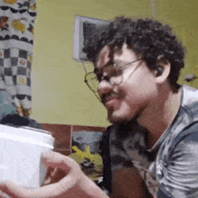 a man wearing glasses and ear buds is holding a toaster in his hand .