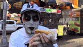 a man wearing a ny hat eating a hotdog