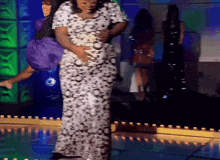 a woman in a leopard print dress is standing on a stage holding her belly