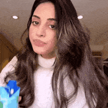 a woman in a white sweater is holding a carton of juice