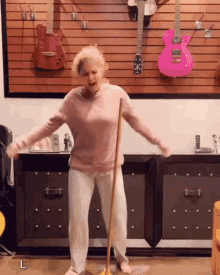 a woman dancing with a mop in front of guitars