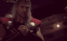 a man with long hair is wearing a red vest and a red cape