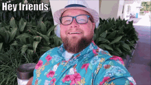 a man with a beard wearing a hawaiian shirt and a hat says hey friends