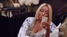 a woman is sitting on a couch holding a cell phone in her hand .