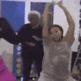 a woman in a grey shirt is dancing with her arms up