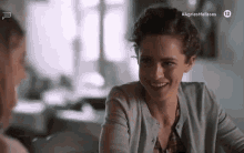 a woman is sitting at a table with another woman and smiling .