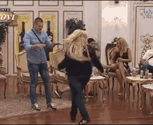 a man and woman are dancing in a room with a sign that says ovi