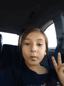a girl giving a peace sign while sitting in a car